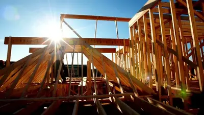 Builder working on the roof framing of a new home at sunrise