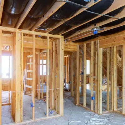 Interior stripped down to bare wood studs with a ladder standing in the room