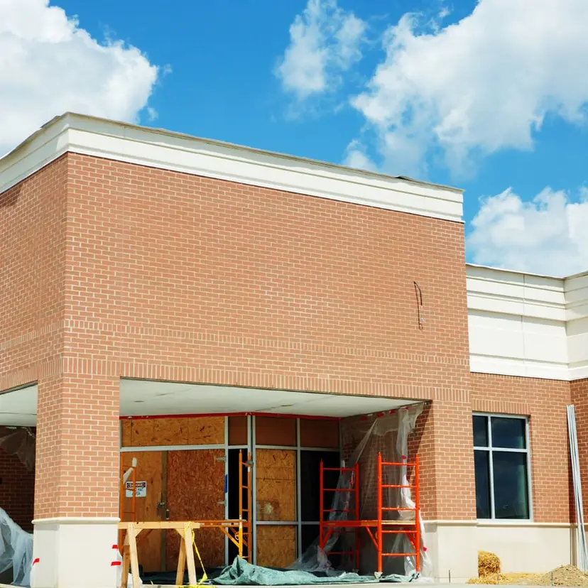 Brick commercial building under construction with open window and door bays