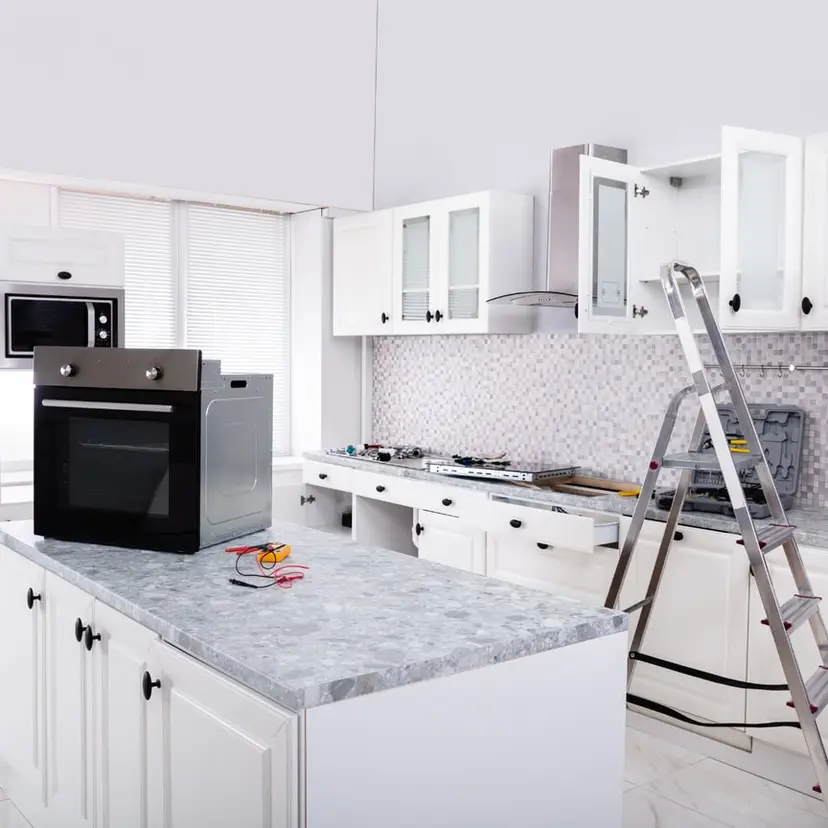 White kitchen mid-renovation with a ladder and unfinished cabinets