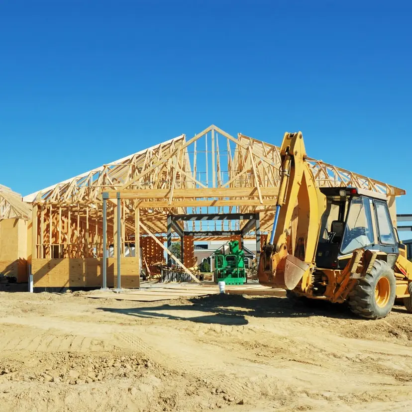 New home being framed with a backhoe on site